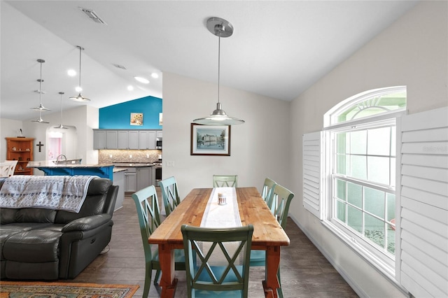 dining space with dark wood-type flooring and vaulted ceiling