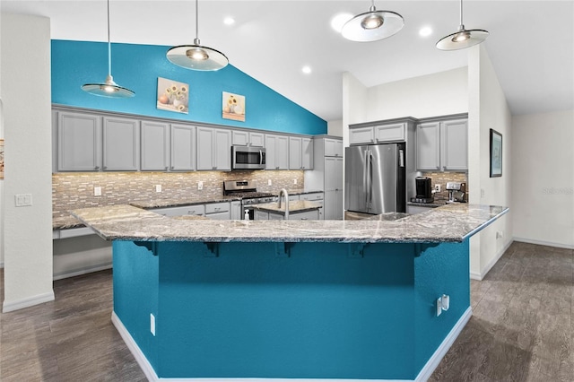 kitchen with decorative light fixtures, stainless steel appliances, decorative backsplash, a kitchen breakfast bar, and gray cabinets