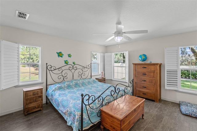 bedroom with ceiling fan, a textured ceiling, and dark hardwood / wood-style flooring