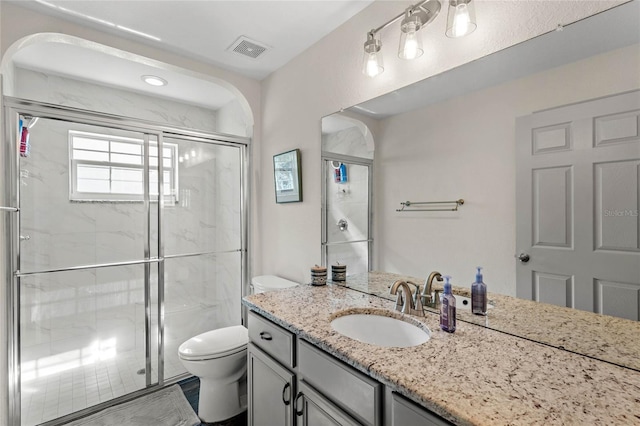 bathroom with an enclosed shower, vanity, and toilet