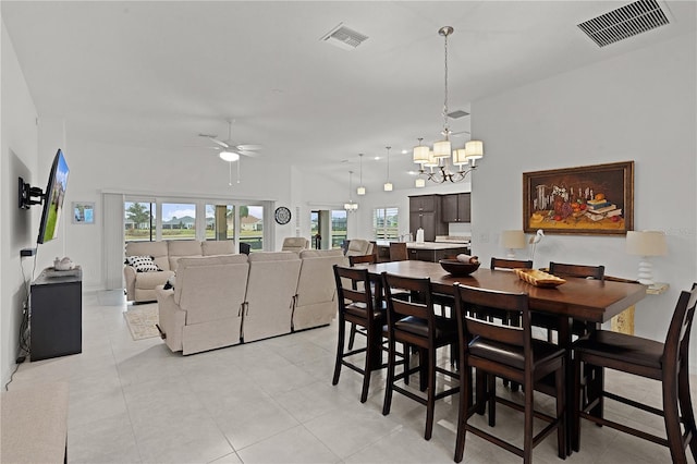 tiled dining space featuring a wealth of natural light and ceiling fan with notable chandelier