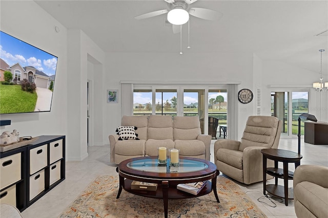 living room featuring lofted ceiling, plenty of natural light, light tile patterned floors, and ceiling fan with notable chandelier