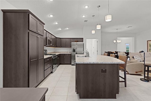 kitchen featuring stainless steel appliances, pendant lighting, an island with sink, lofted ceiling, and light tile patterned flooring