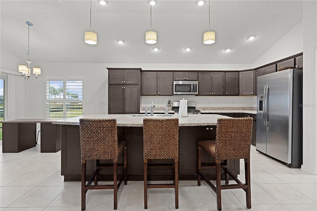 kitchen featuring a center island with sink, lofted ceiling, stainless steel appliances, and hanging light fixtures