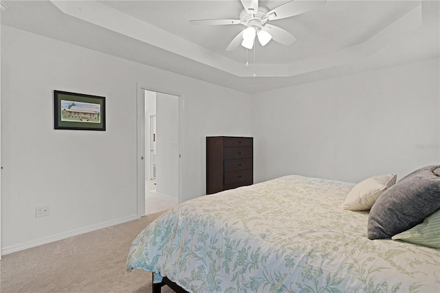 bedroom with a tray ceiling, ceiling fan, and light colored carpet