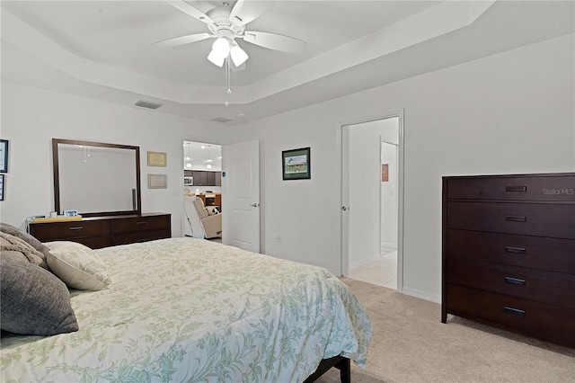 bedroom with light colored carpet, ceiling fan, and a tray ceiling