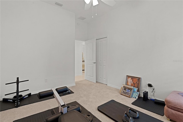 workout area with light carpet, a towering ceiling, and ceiling fan