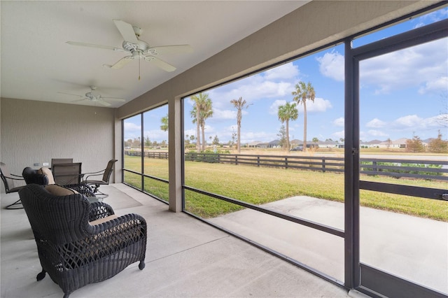 sunroom featuring ceiling fan, a rural view, and a wealth of natural light