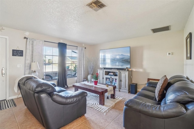 living area with light tile patterned floors, baseboards, visible vents, and a textured ceiling