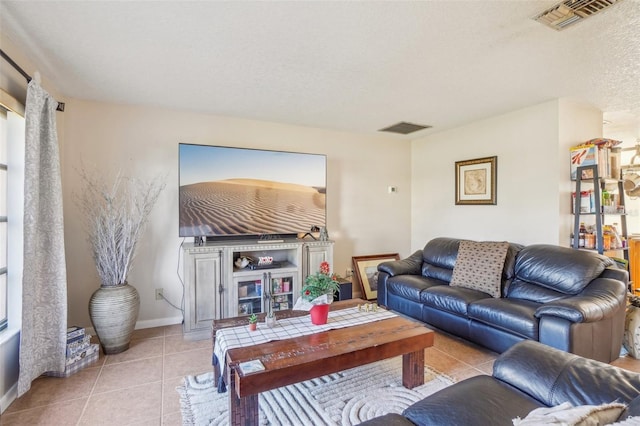 living room featuring light tile patterned floors, baseboards, visible vents, and a textured ceiling