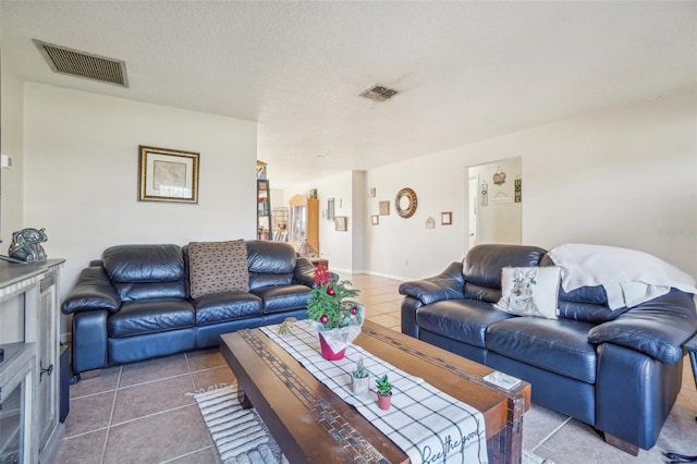 tiled living room with visible vents and a textured ceiling