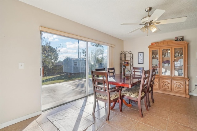 dining area featuring ceiling fan, light tile patterned floors, a textured ceiling, and baseboards