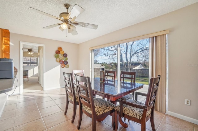 dining room with light tile patterned floors, a ceiling fan, baseboards, and a textured ceiling