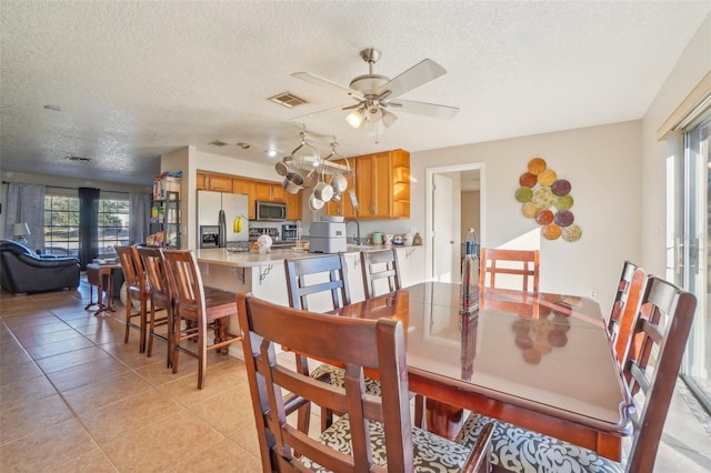 dining space with visible vents, ceiling fan, a textured ceiling, and light tile patterned floors