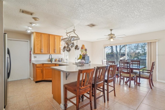 kitchen featuring light countertops, freestanding refrigerator, visible vents, and a peninsula