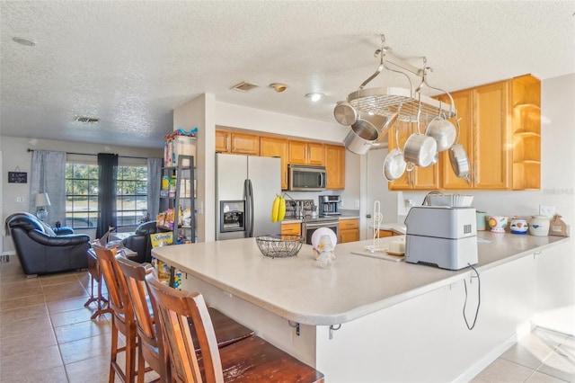 kitchen featuring visible vents, appliances with stainless steel finishes, open floor plan, a peninsula, and light countertops