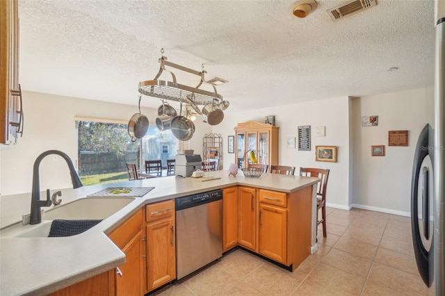 kitchen with light tile patterned floors, light countertops, visible vents, stainless steel dishwasher, and a sink