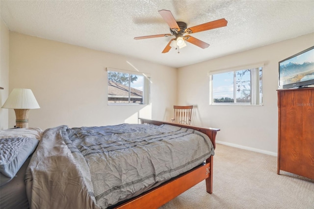 bedroom featuring a ceiling fan, light carpet, baseboards, and multiple windows