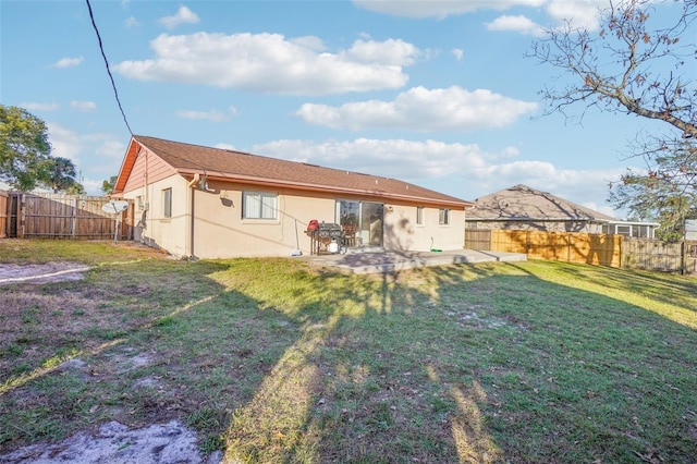 rear view of house with a yard, a patio, a fenced backyard, and stucco siding