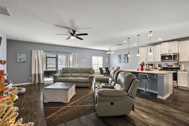 living room featuring ceiling fan, dark wood-type flooring, and a textured ceiling