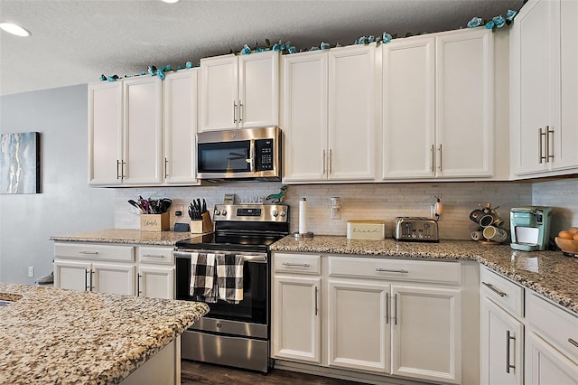 kitchen featuring stainless steel appliances, tasteful backsplash, and white cabinets