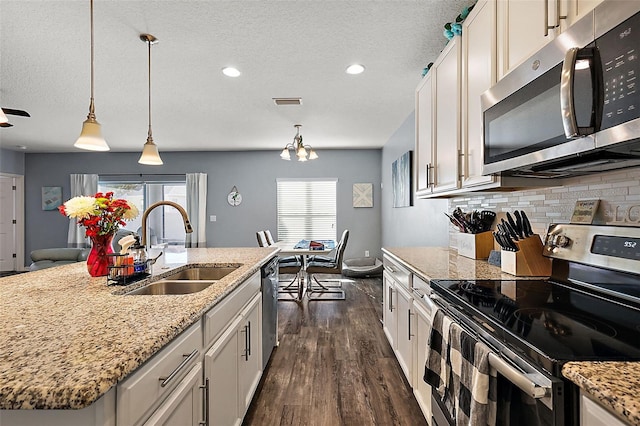 kitchen with sink, white cabinetry, stainless steel appliances, a kitchen island with sink, and backsplash