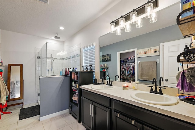 bathroom featuring tiled shower, vanity, tile patterned flooring, and a textured ceiling