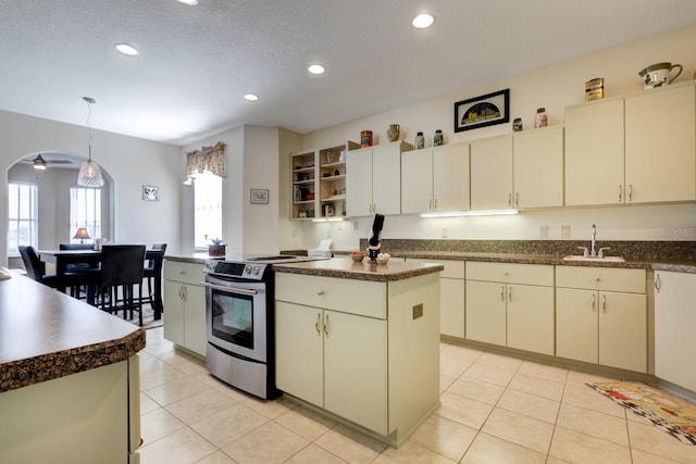 kitchen featuring ceiling fan, sink, electric range, a kitchen island, and hanging light fixtures