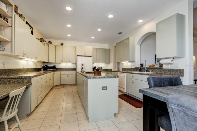 kitchen featuring a center island, light tile patterned flooring, white appliances, and sink