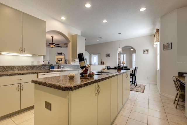 kitchen featuring a textured ceiling, ceiling fan, sink, cream cabinets, and a kitchen island