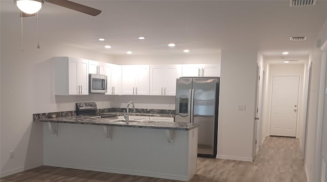 kitchen with stainless steel appliances, kitchen peninsula, sink, and white cabinets