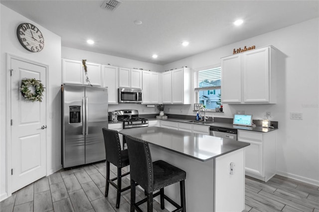 kitchen featuring a center island, sink, stainless steel appliances, a breakfast bar, and white cabinets