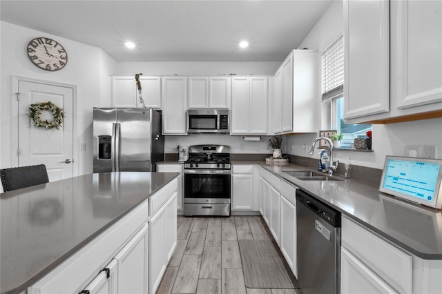 kitchen featuring white cabinetry, sink, stainless steel appliances, and light hardwood / wood-style flooring