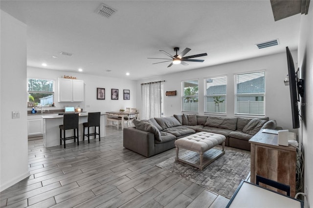 living room with ceiling fan and light wood-type flooring