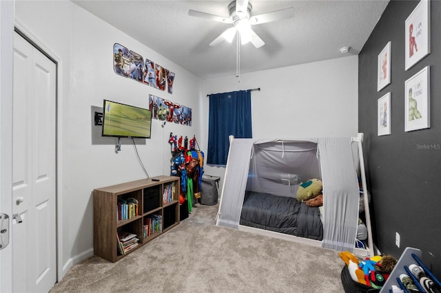 playroom with ceiling fan, light colored carpet, and a textured ceiling