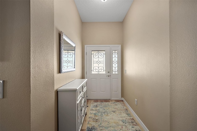 doorway to outside with a textured ceiling and light wood-type flooring