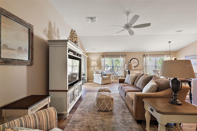 living room with a textured ceiling, hardwood / wood-style flooring, vaulted ceiling, and ceiling fan