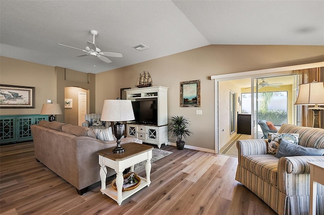 living room featuring ceiling fan, light hardwood / wood-style flooring, and vaulted ceiling