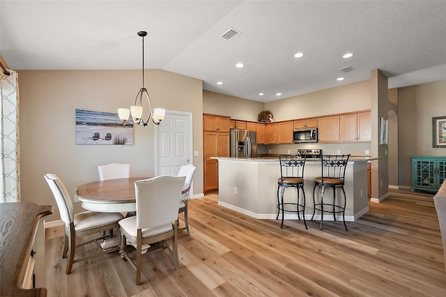 dining room with a chandelier, light hardwood / wood-style floors, and lofted ceiling