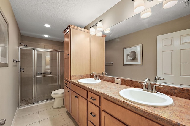 bathroom featuring a textured ceiling, vanity, a shower with door, tile patterned flooring, and toilet