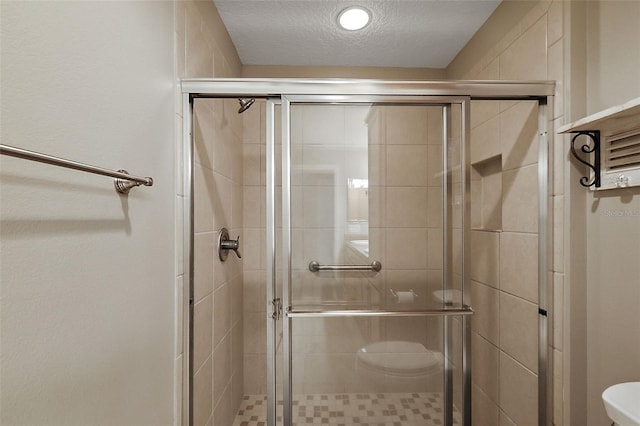 bathroom with an enclosed shower and a textured ceiling