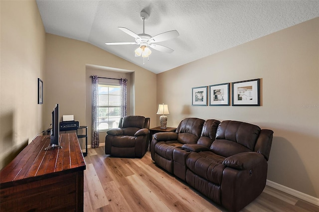 living room featuring a textured ceiling, light hardwood / wood-style floors, ceiling fan, and lofted ceiling