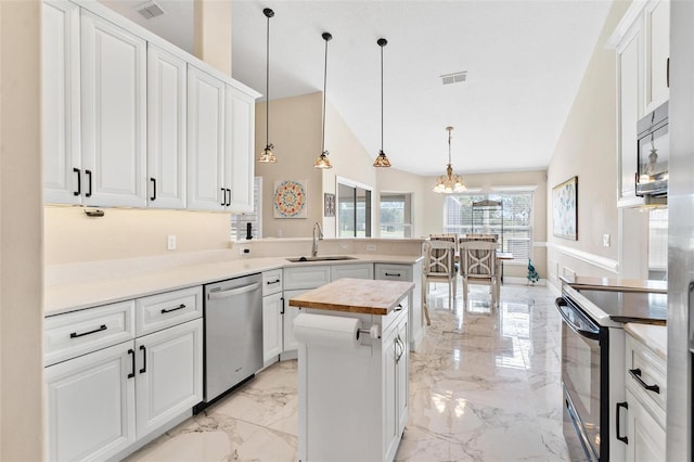 kitchen with sink, a center island, hanging light fixtures, white cabinets, and appliances with stainless steel finishes