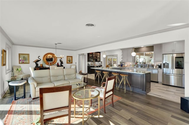 living room featuring an inviting chandelier, ornamental molding, and light hardwood / wood-style flooring