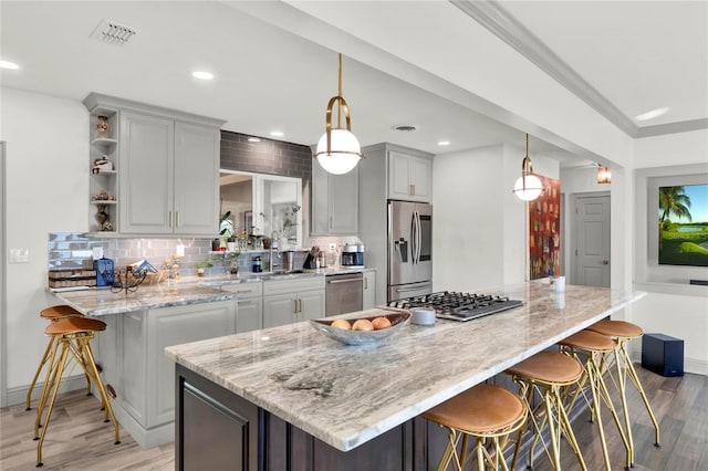 kitchen with a kitchen breakfast bar, light wood-type flooring, stainless steel appliances, and hanging light fixtures