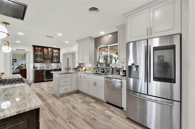 kitchen with white cabinets, decorative backsplash, stainless steel appliances, and hanging light fixtures