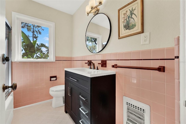 bathroom with vanity, tile patterned floors, toilet, tile walls, and heating unit