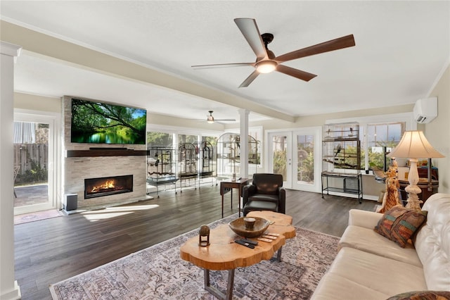 living room featuring a stone fireplace, french doors, dark wood-type flooring, and a wall mounted air conditioner