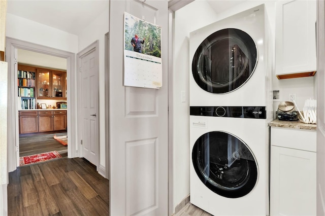 clothes washing area featuring dark wood-type flooring and stacked washing maching and dryer