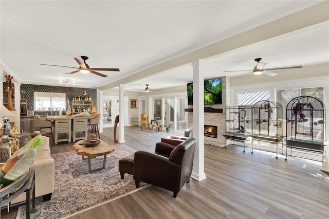 living room with hardwood / wood-style flooring, ornamental molding, a fireplace, and bar